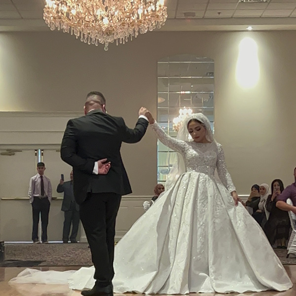 Couple's first dance on the dance floor under a chandelier