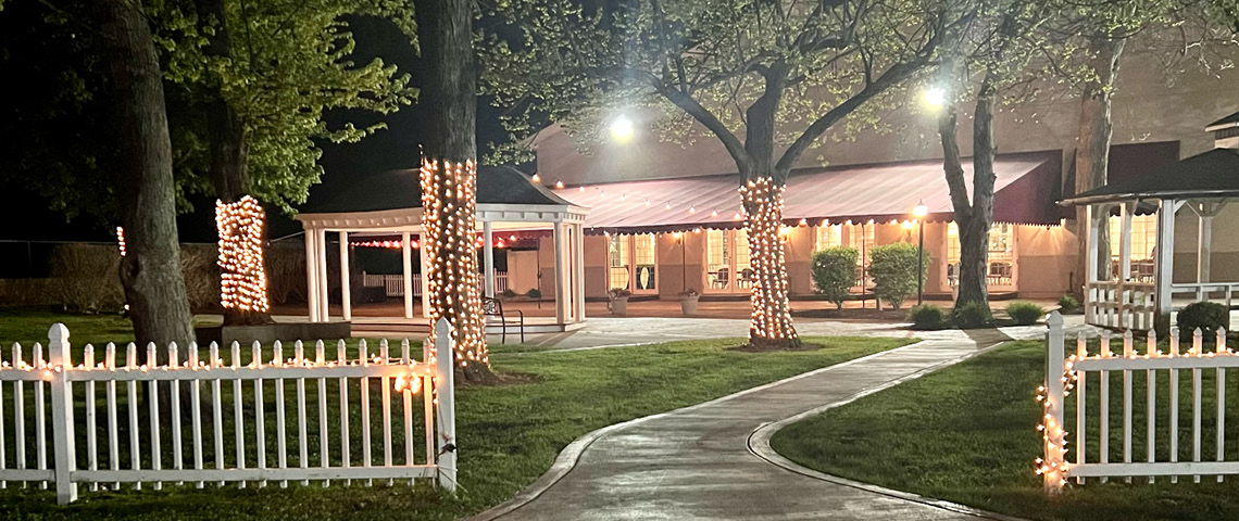 Entrance to patio space with lighted fence and trees