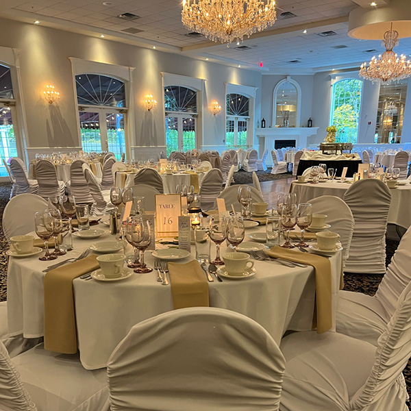 White and beige linens in a large banquet hall with french doors and chandeliers