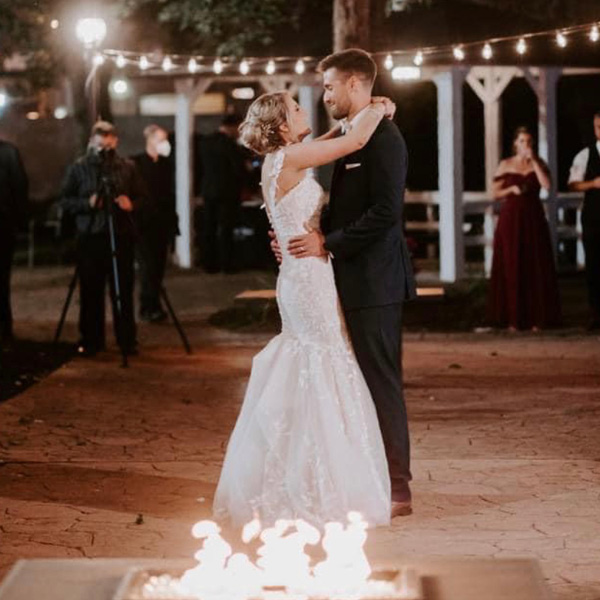 Couple's first dance on a patio with a fire pit and string lights