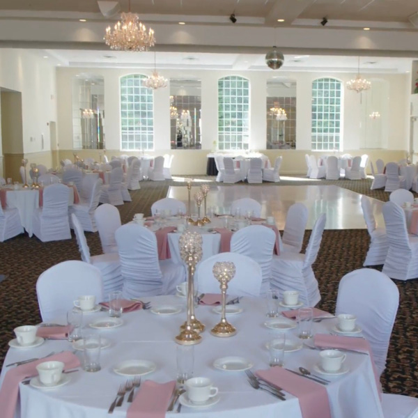 Wedding venue with white and pink linens and a large dance floor
