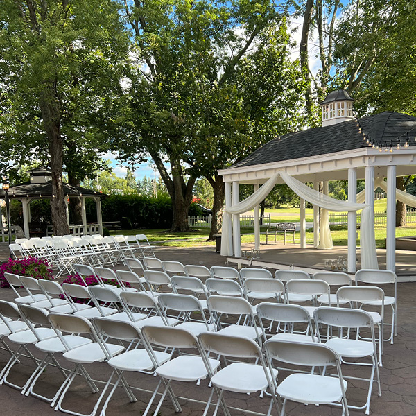 Outdoor event space set up with white chairs and a gazebo