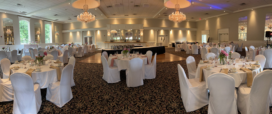 Decorated banquet hall with a buffet table, bar, chandeliers, and tables decorated with hydrangeas