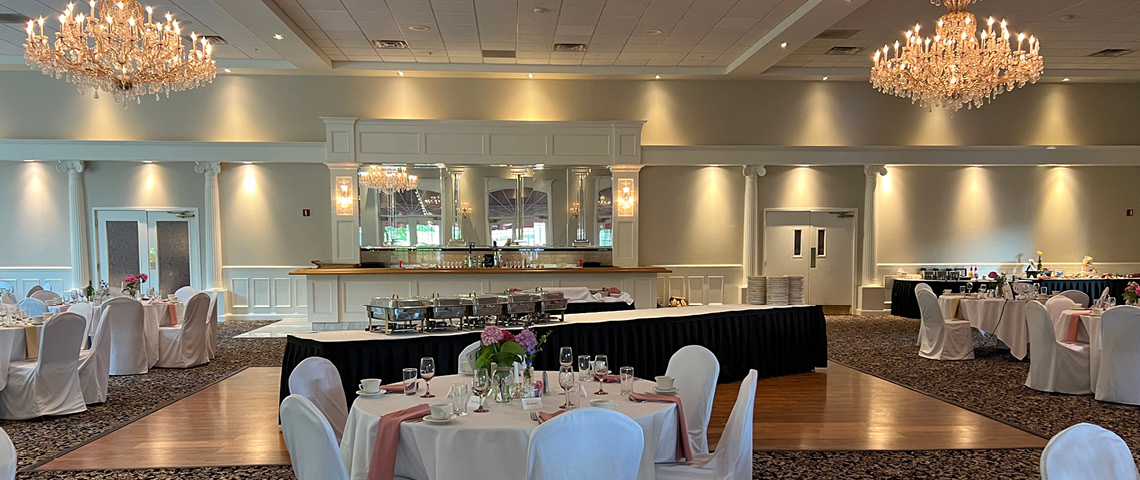 Banquet hall decorated for a wedding with large chandeliers and a buffet table